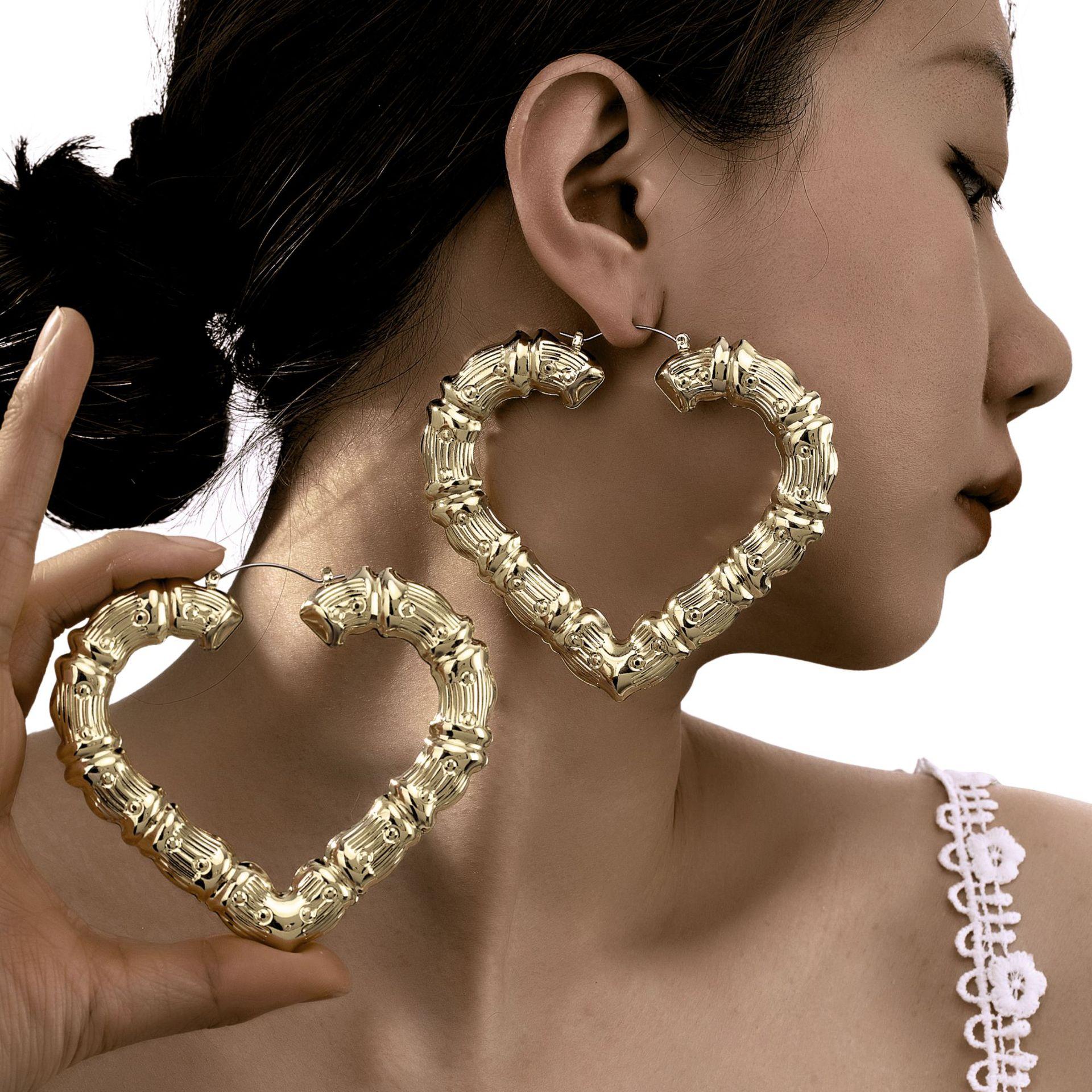 Woman wearing gold bamboo heart earrings